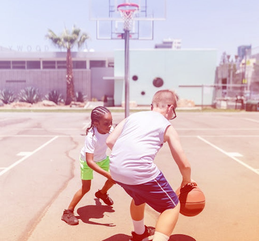 Deux jeunes jouent au basketball, l'un dribble le ballon